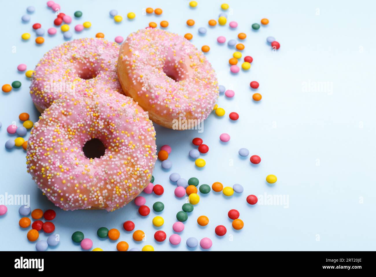 Pink doughnuts and candies on blue background, copy space flat lay Stock Photo