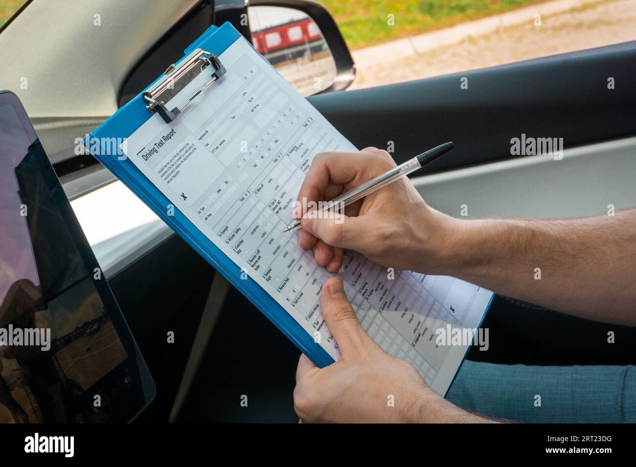 Male instructor filling out the driving test report while sitting in