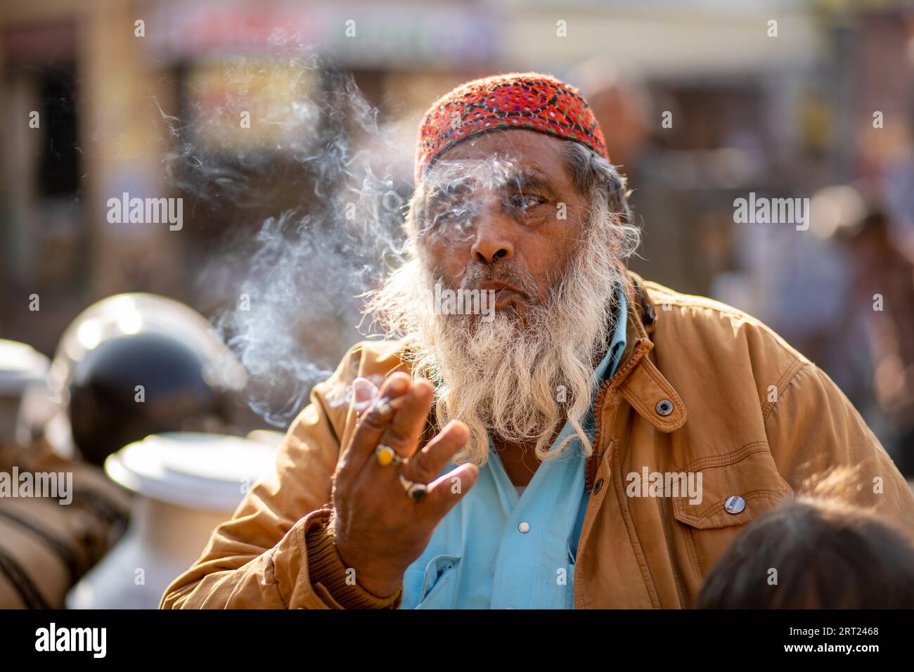 Jaisalmer, India, December 7, 2019: Portrait of an elderly Rajasthani man blowing cigarette smoke Stock Photo