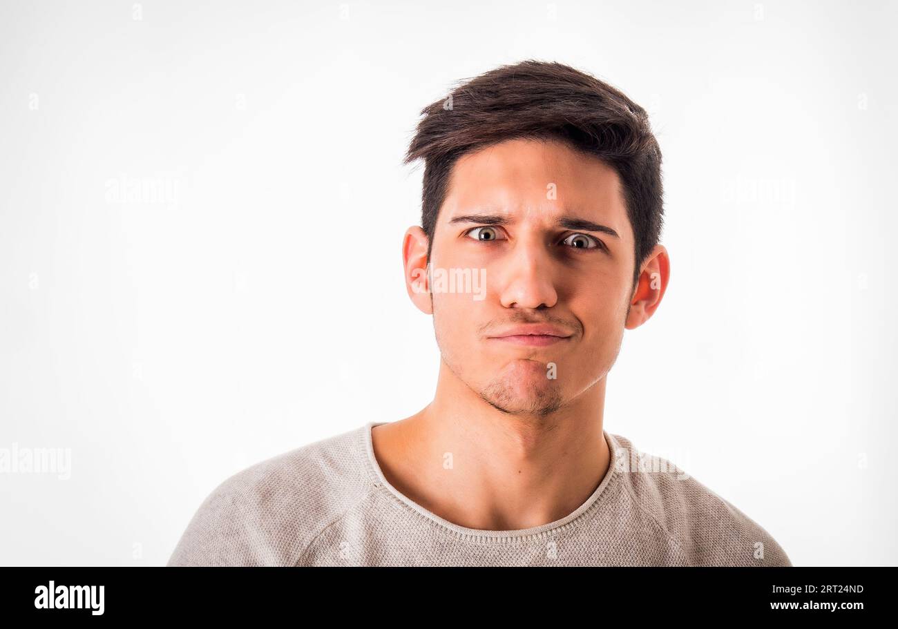Young guy with short dark hair making confused face expression while looking at camera with doubt against white background Stock Photo