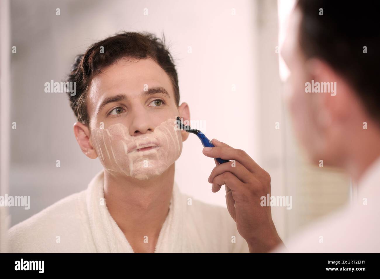 Portrait of young man shaving face after morning shower Stock Photo Alamy