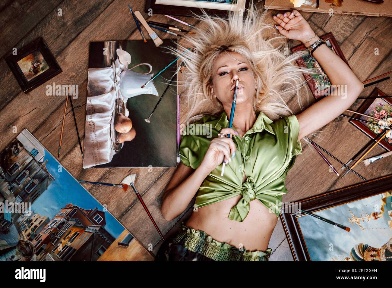 Top view of a young blonde woman painter, surrounded by her artwork Stock Photo