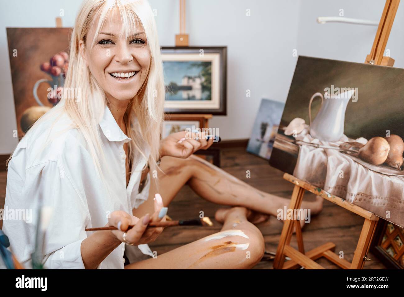 Young, blonde woman painter showing her artwork Stock Photo