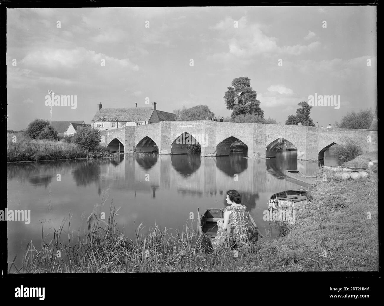 New Bridge, Newbridge, Northmoor, West Oxfordshire, Oxfordshire, 1945-1960. View of the bridge from the south-west, with a woman sitting in a rowing boat in the foreground. Stock Photo