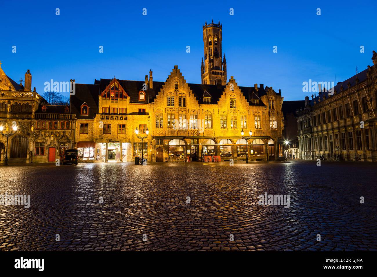 BRUGES, BELGIUM - 19th FEBRUARY 2016: Buildings in Burg Square in Bruges at dusk with a blue sky. The Belfry of Bruges can be seen in the distance. Stock Photo