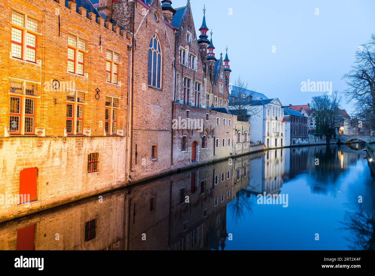 A view along the Groenerei and Steenhouwersdijk part of the Bruges canals at twilight. The outside of buildings can be seen and reflections can be see Stock Photo