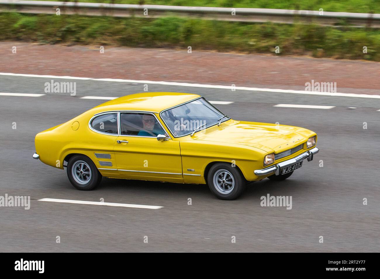 1971 70s seventies Daytona Yellow Ford Capri 1599cc coupe; travelling at speed on the M6 motorway in Greater Manchester, UK Stock Photo