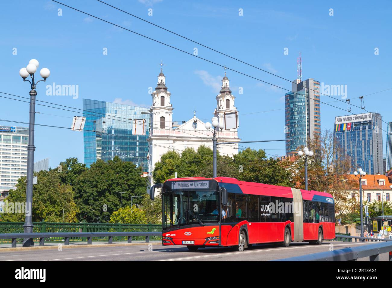 VILNIUS, LITHUANIA - 3RD SEPT 2023: A common red public transportation bus in Vilnius during the day with architecture in the background. People can b Stock Photo