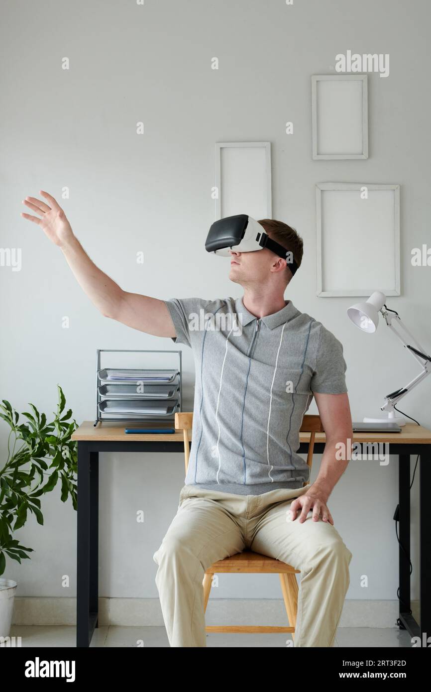 Developer in headset testing new virtual reality application at home Stock Photo