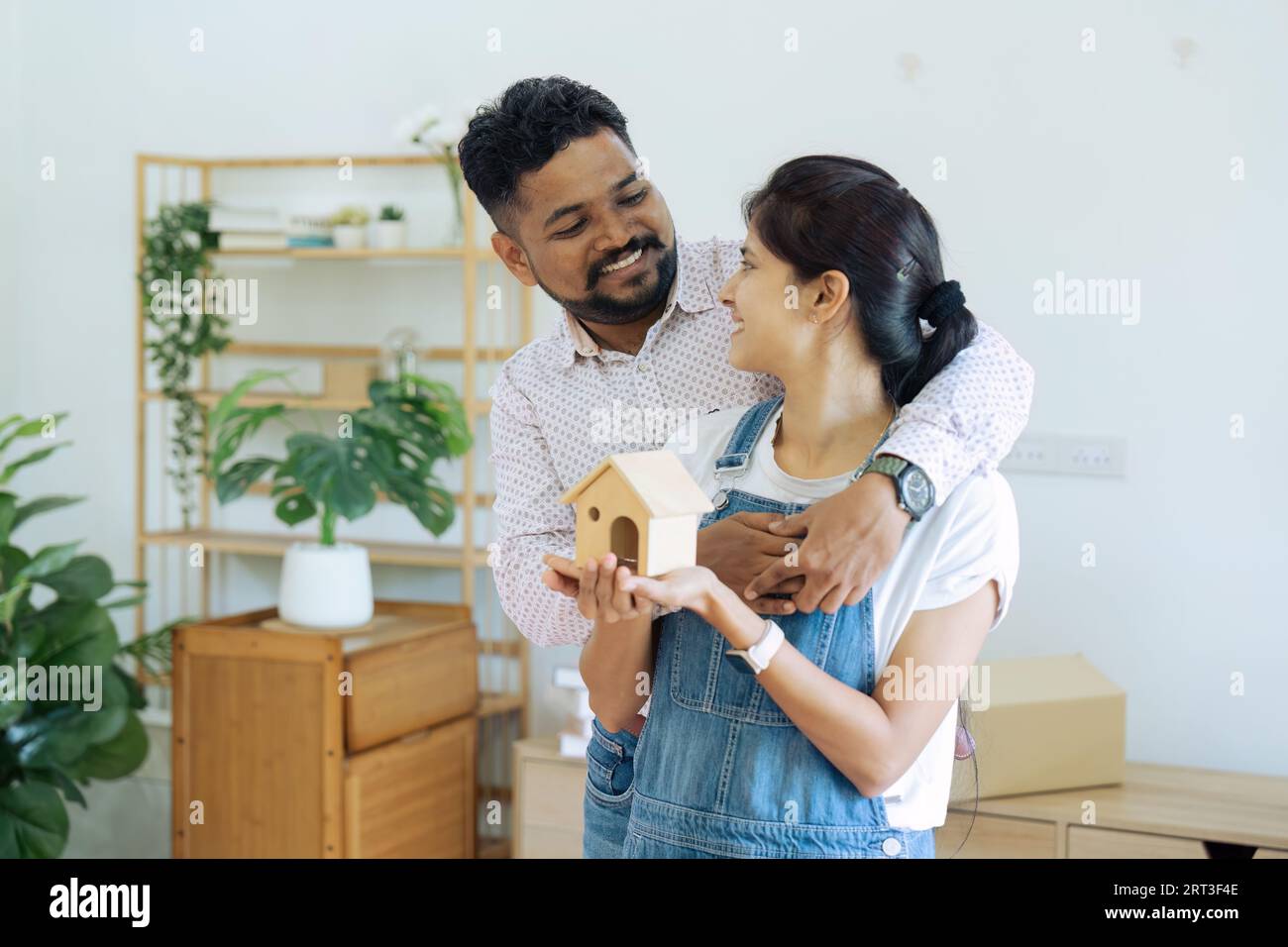 Married Indian couple owners holding house model moving in new home ...