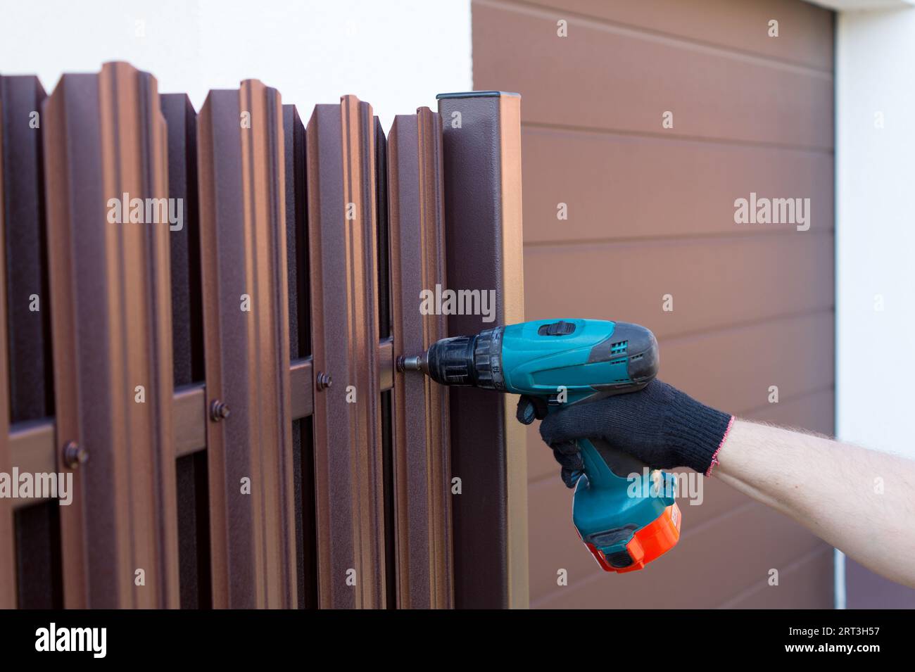 Screwing roofing screws into a metal picket fence by using cordless