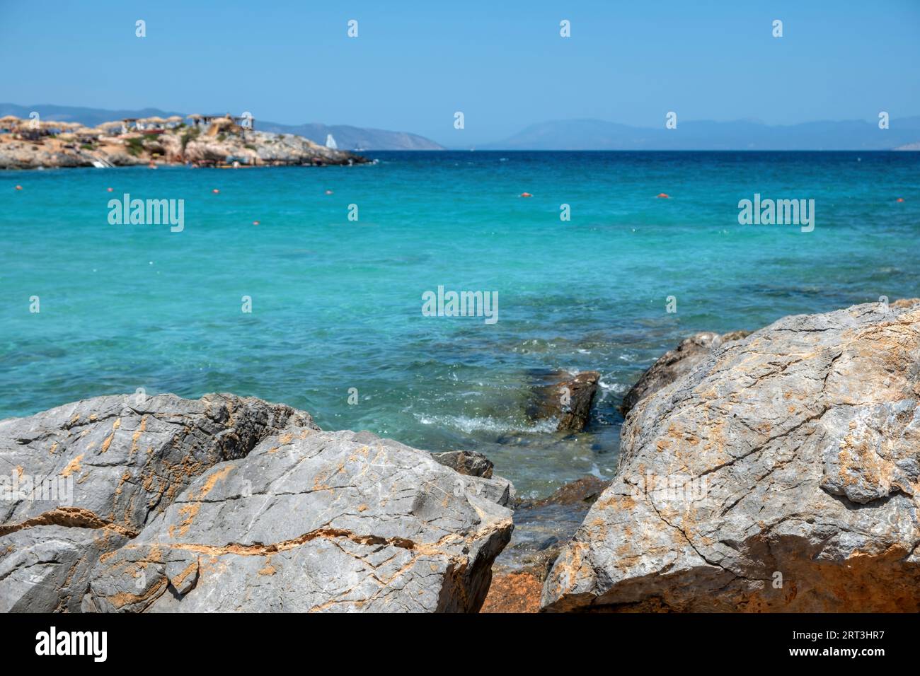 Aponisos beach Greece Agistri island. Clear view of big rock at seaside, turquoise sea water, blur rocky beach background. Summer day. Stock Photo