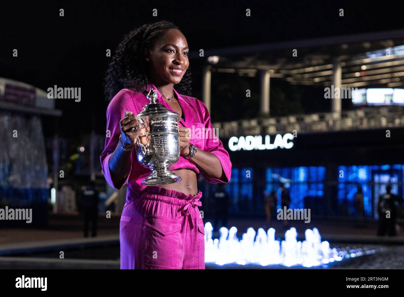 Coco Gauff winner of women's championship of US Open poses with trophy in front of fountain at