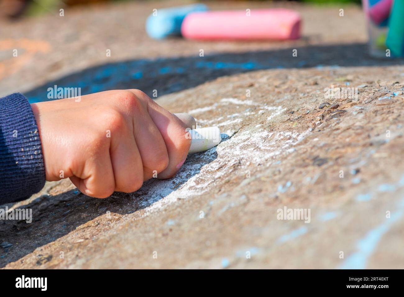 The child drawing a chalk on asphalt Stock Photo - Alamy