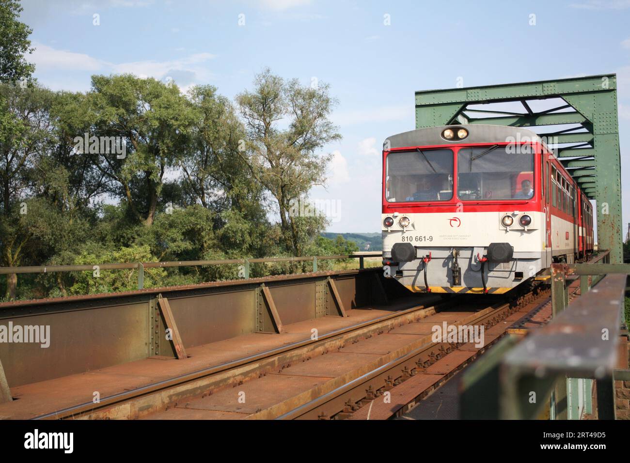 A diesel-fuelled train passing on a one-track railway bridge in Komárany, Slovakia. Stock Photo