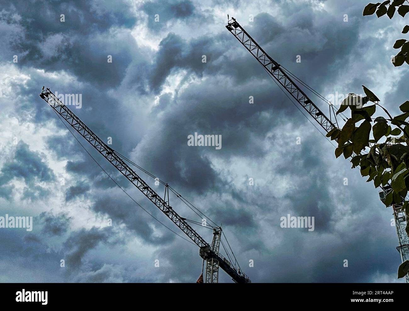 Construction cranes against a stormy sky Stock Photo