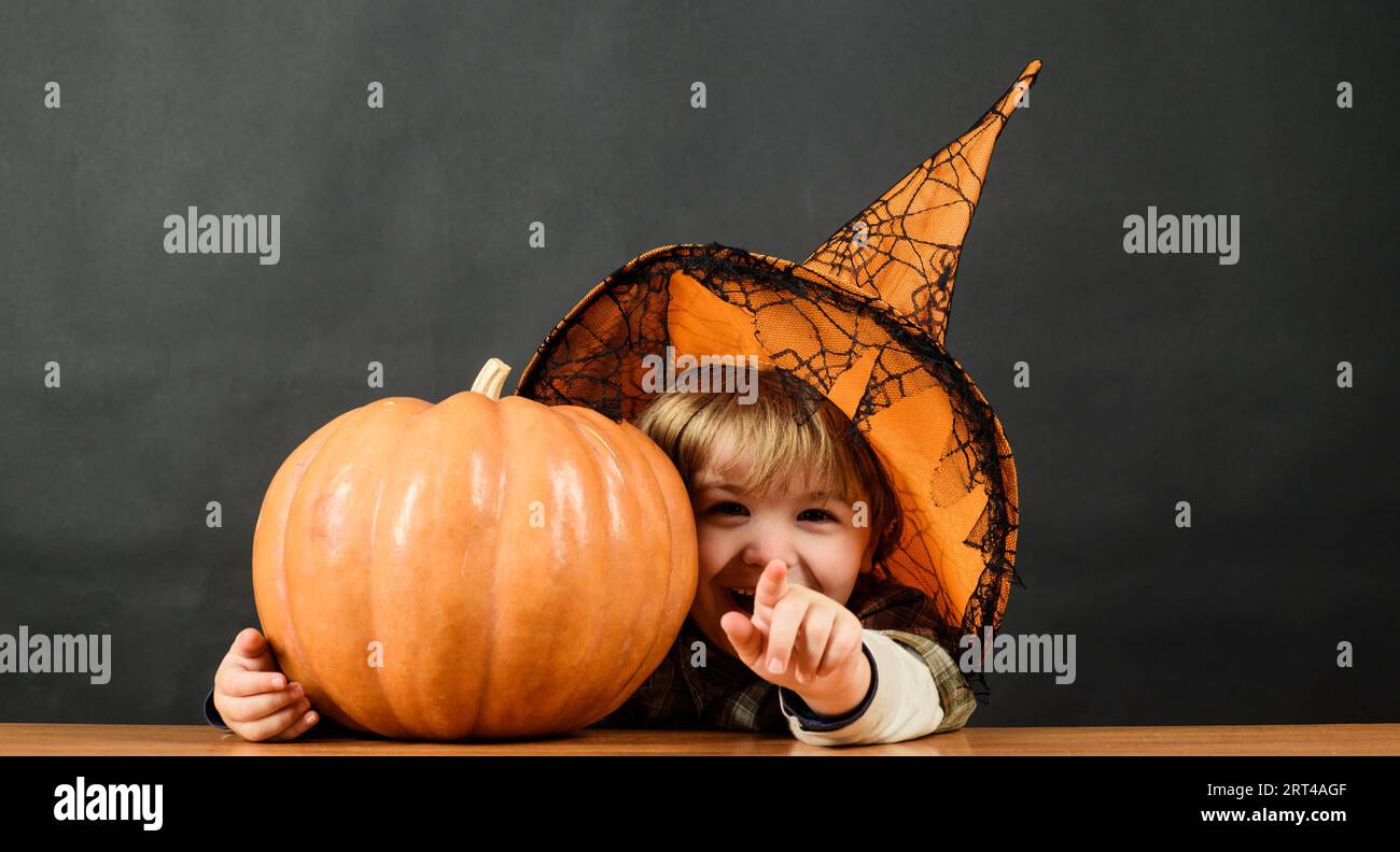 Child with pumpkin on Halloween holiday. Little boy in witch hat with halloween jack-o-lantern. Preparation for Halloween holidays. Halloween kid with Stock Photo