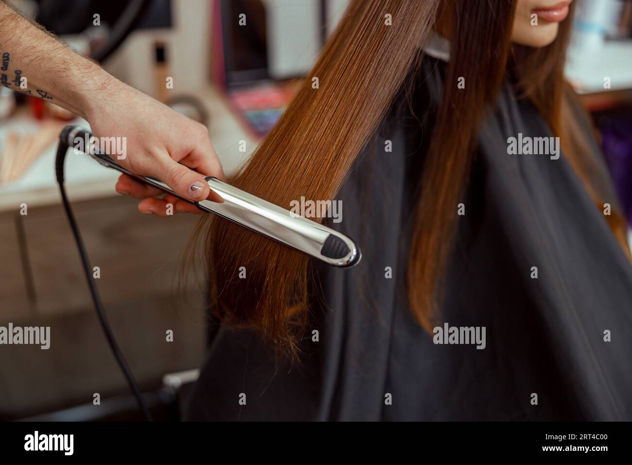 Closeup of hairdresser hand holding hair straightener and making