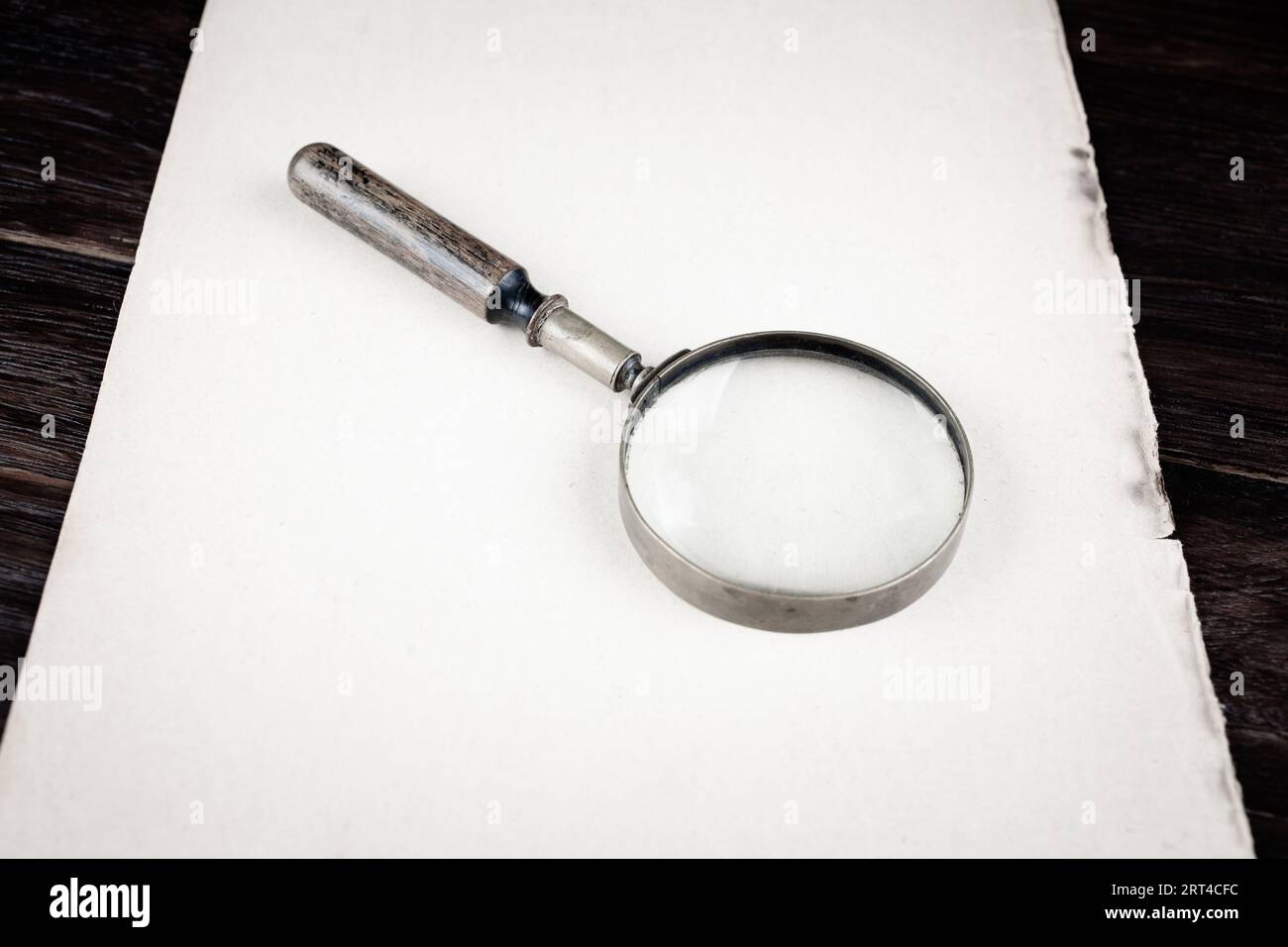Antique vintage magnifying glass on paper background Stock Photo - Alamy