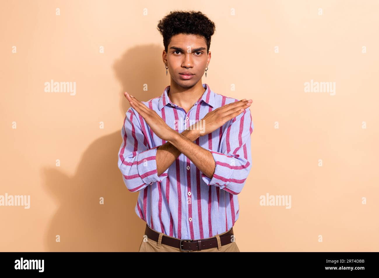 Portrait of serious strict young worker guy hold crossed hands against ...