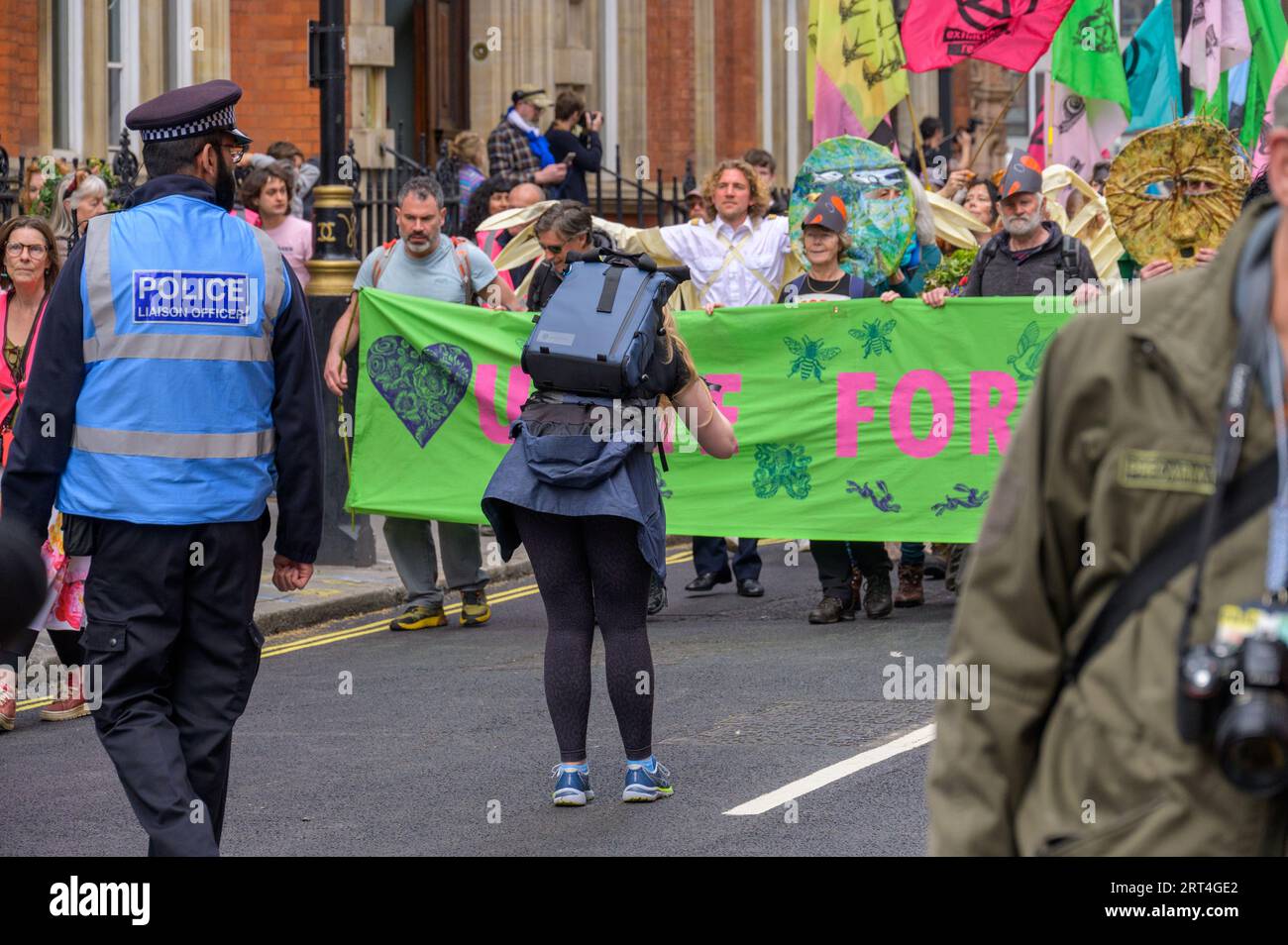 LONDON - April 22, 2023: Female photographer captures Extinction Rebellion protest, focusing on the protest banner at the front of the march, with a M Stock Photo