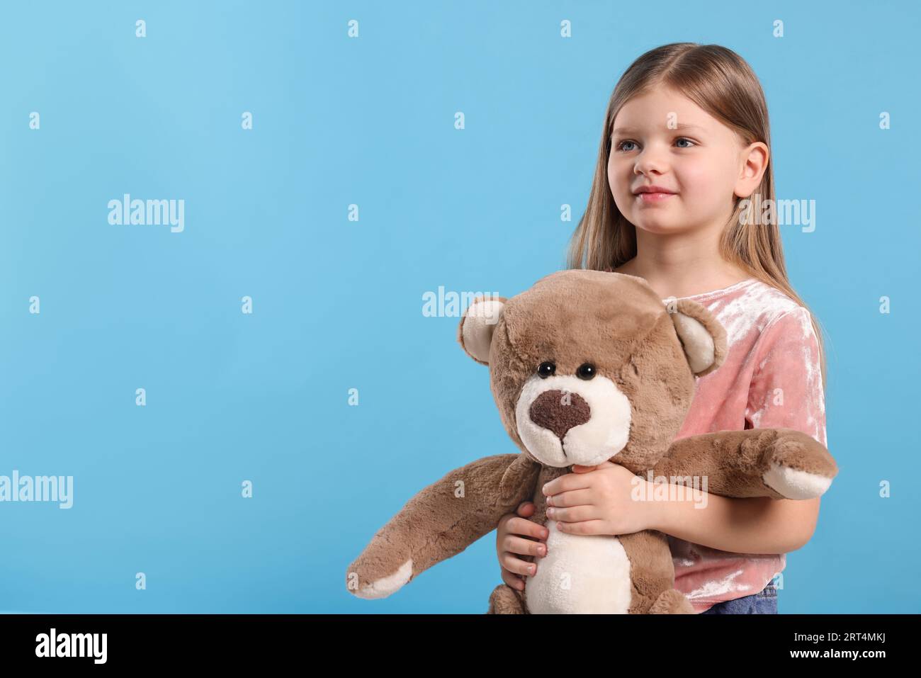 Cute little girl with teddy bear on light blue background. Space for ...