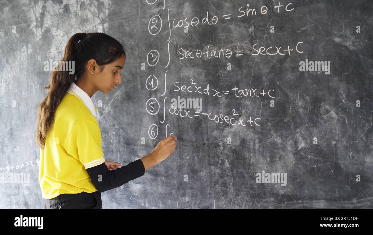 Happy Indian school girl child standing  in front of black chalkboard background. Education Concept or Back to School Stock Photo