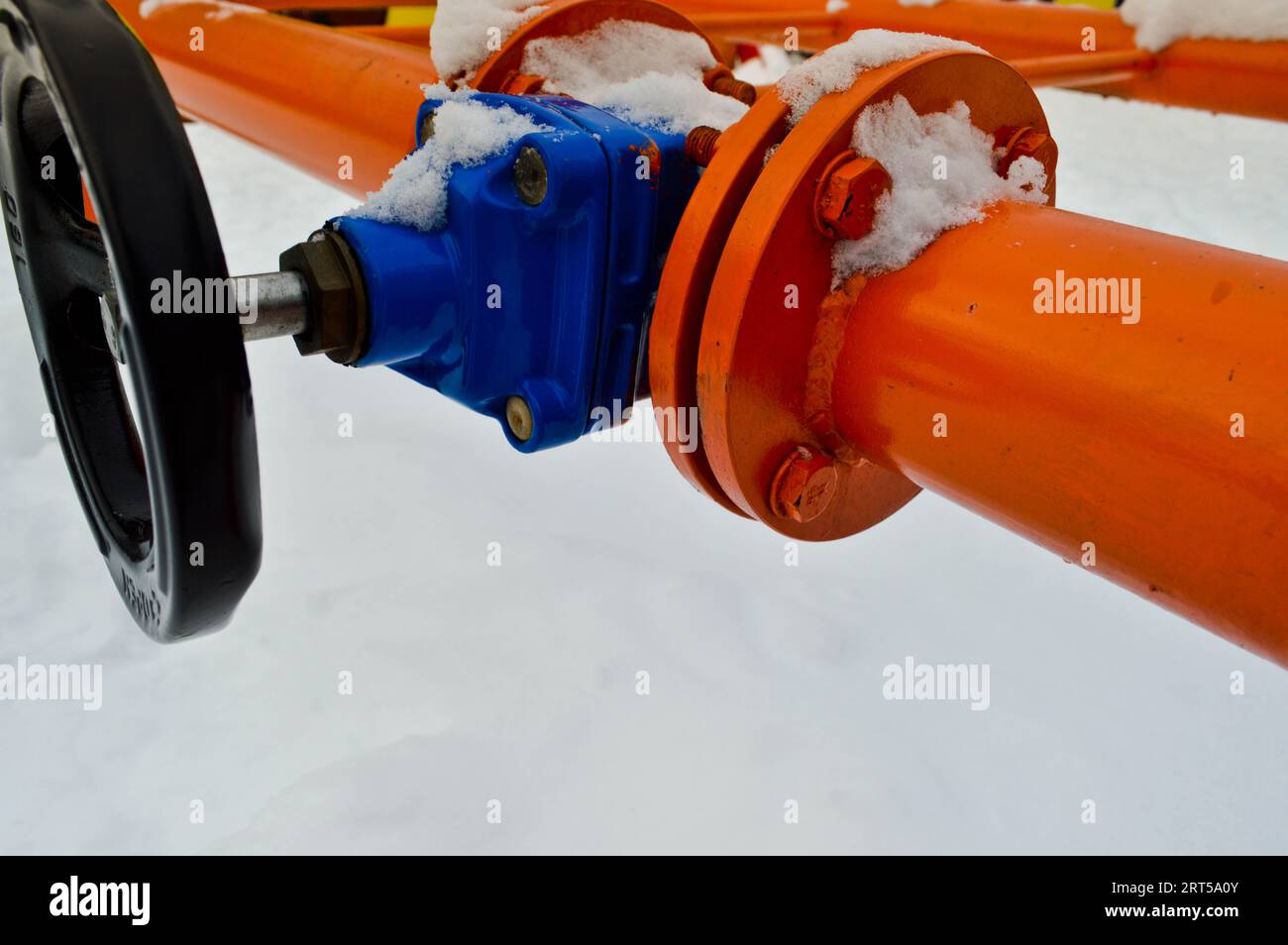 Industrial shut-off regulating protective pipe fittings. Black valve for opening, closing on an iron orange metal pipe with flanges, studs, nuts again Stock Photo