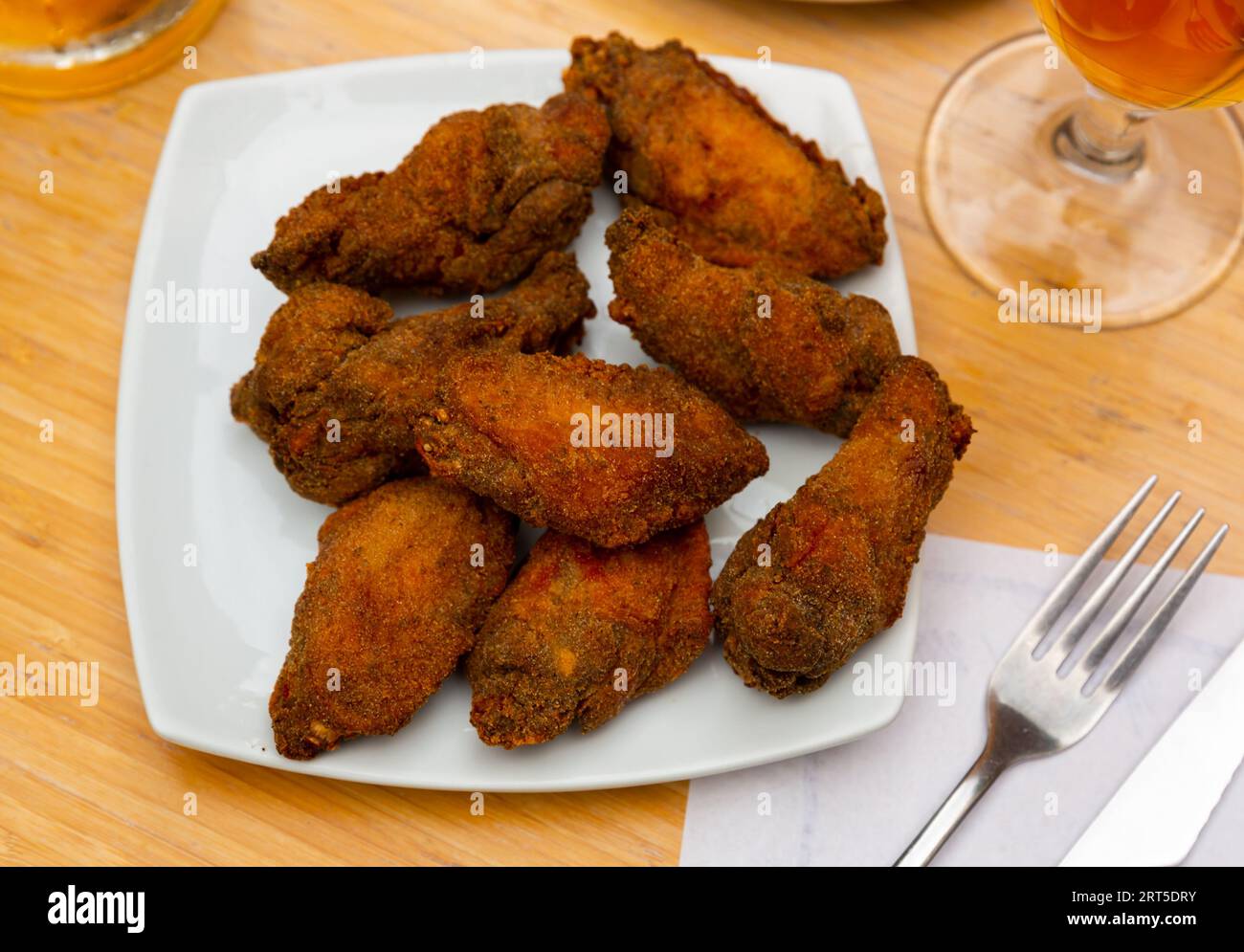 Fried chicken wings in breadcrumbs on square white plate Stock Photo