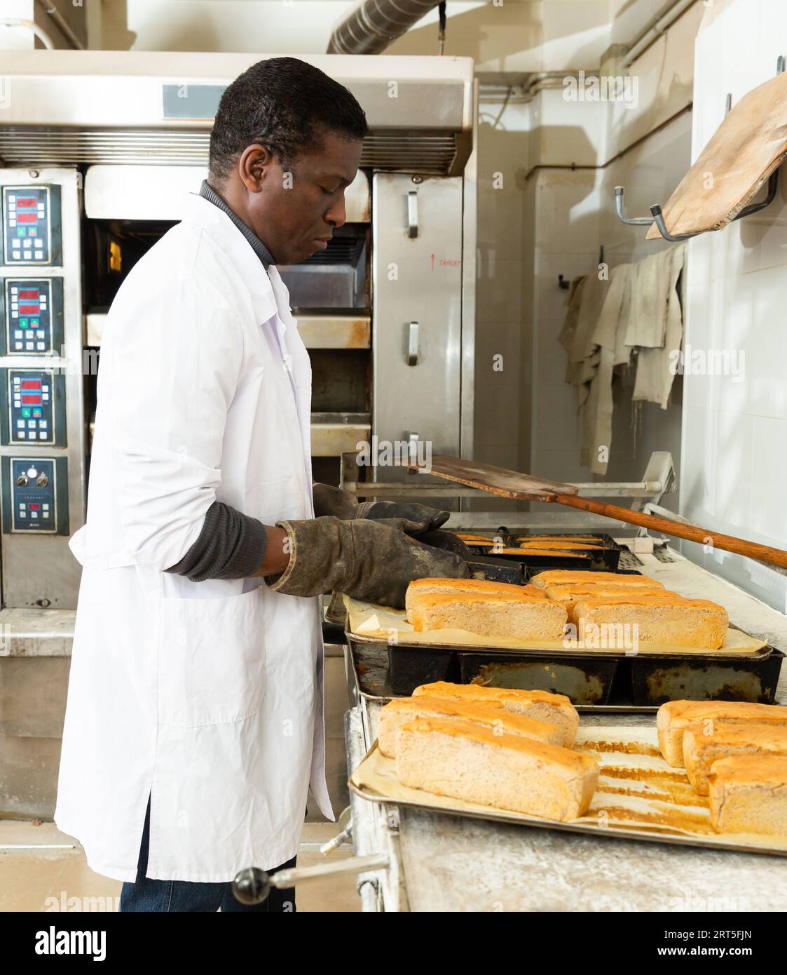 African baker taking out bread from baking molds Stock Photo