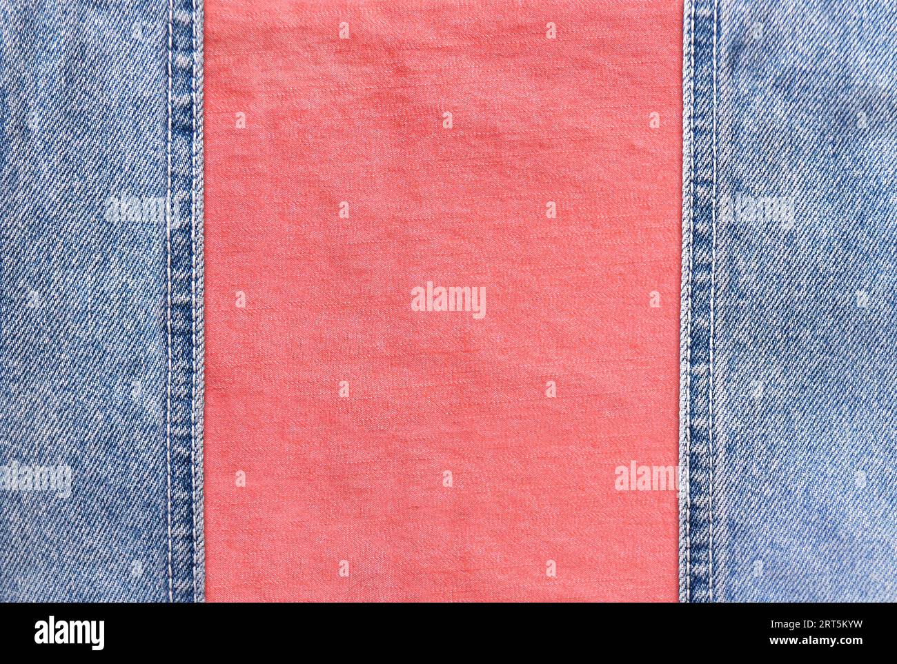 Blue denim borders with a seam and coral cotton texture. Light blue and pink color denim jeans fabric. Copy space for text Stock Photo