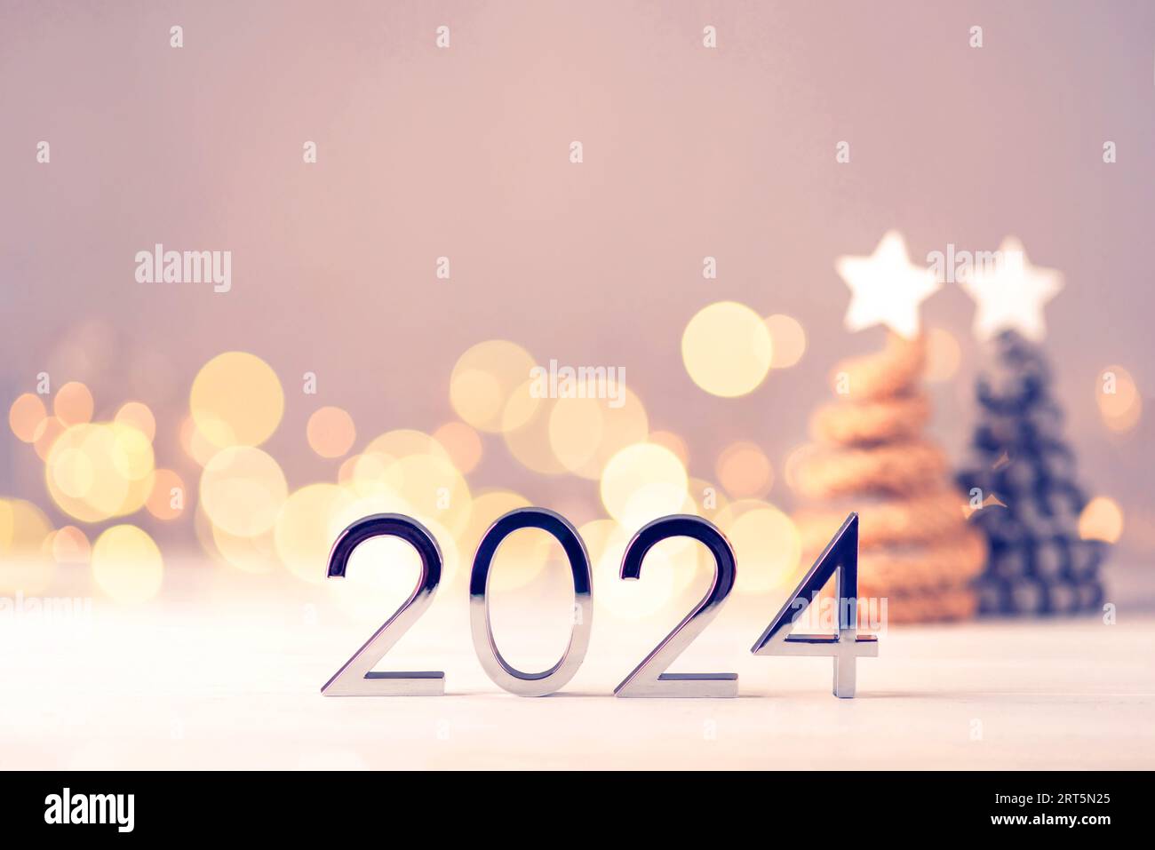 Metal numbers 2024 on a white table with Christmas trees and bokeh