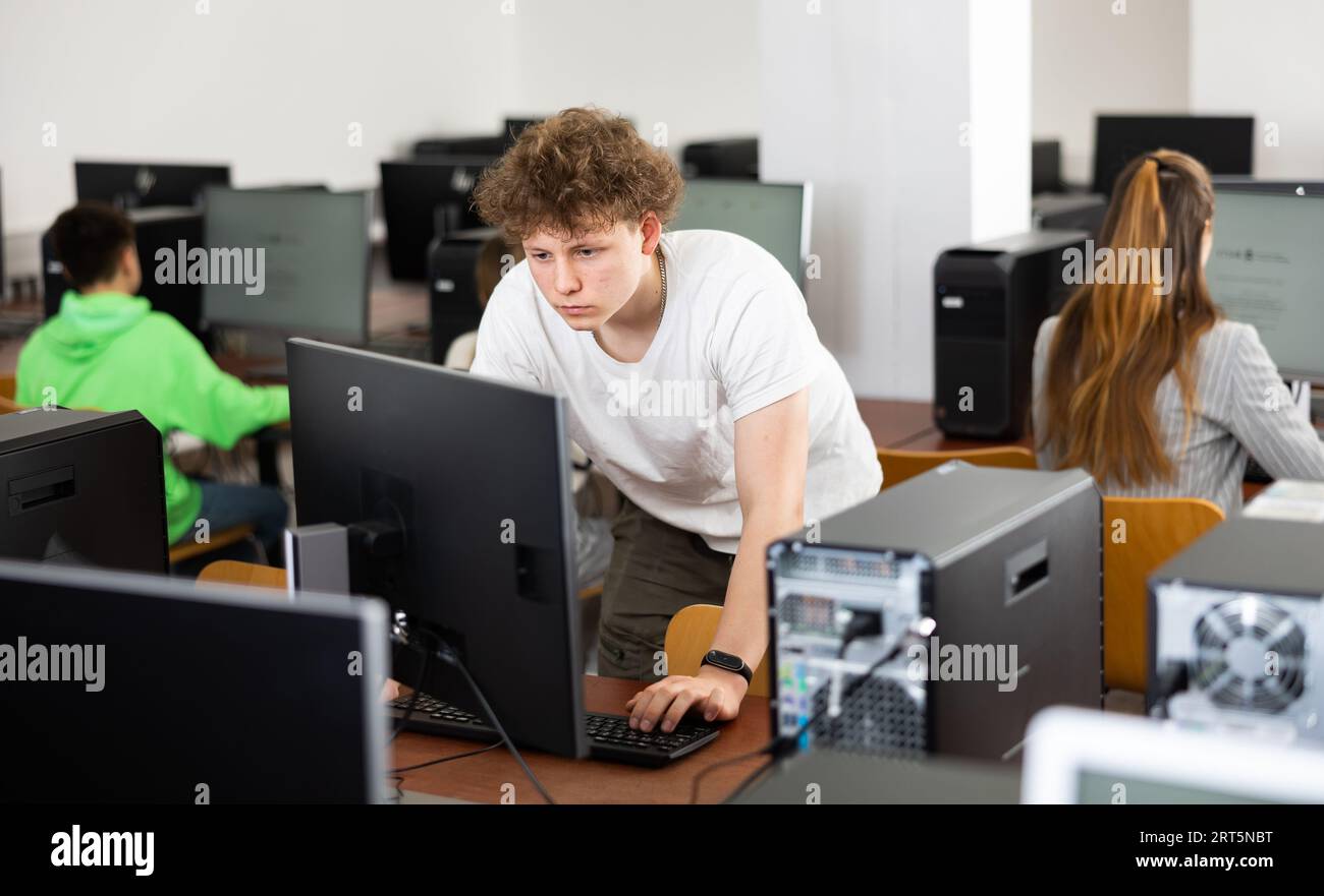 Focused teenager studying with classmates in computer lab Stock Photo ...