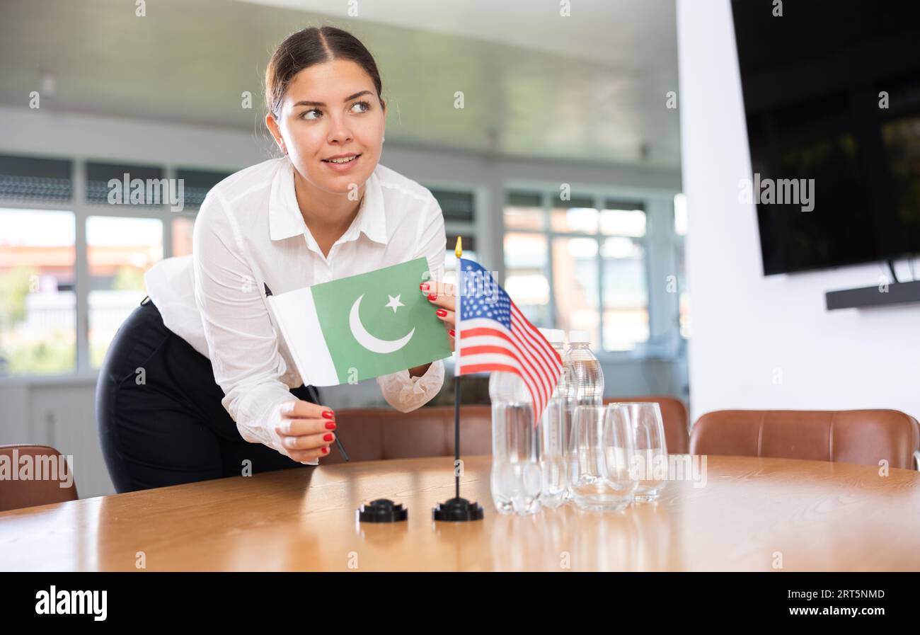 Young woman putting flags of Pakistan and USA on table in office Stock Photo