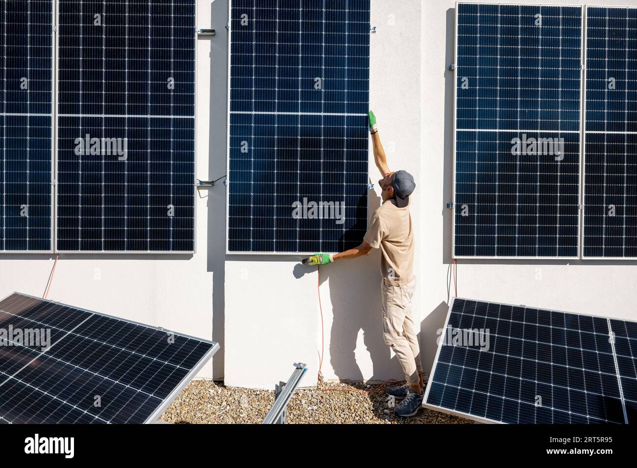Man installing solar panels on a rooftop Stock Photo