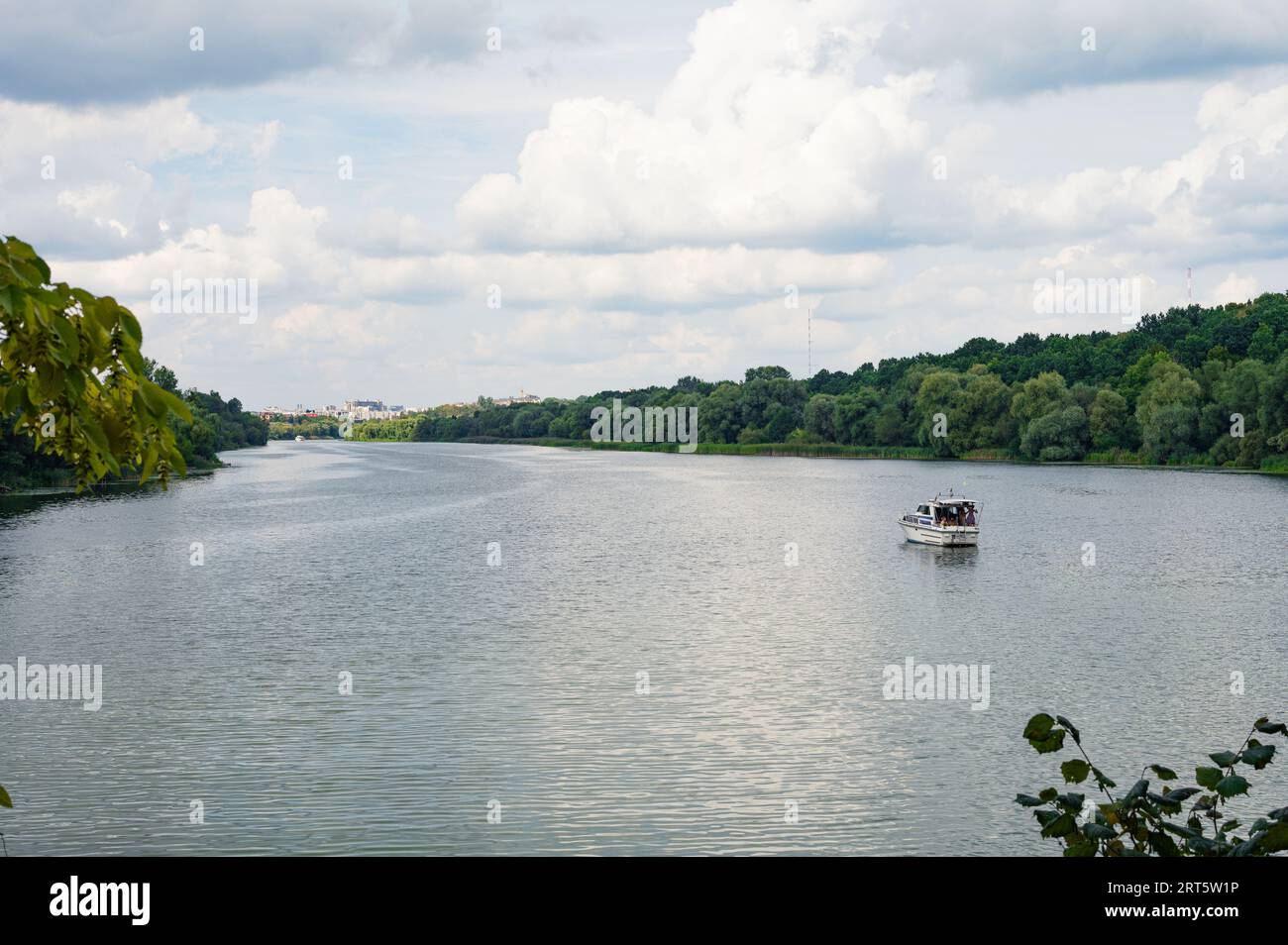 Yacht boat on river with lush green forest on bank, sky and town far away on background. Scenic, beautiful, card view, wallpaper, Vinnytsia, Ukraine Stock Photo