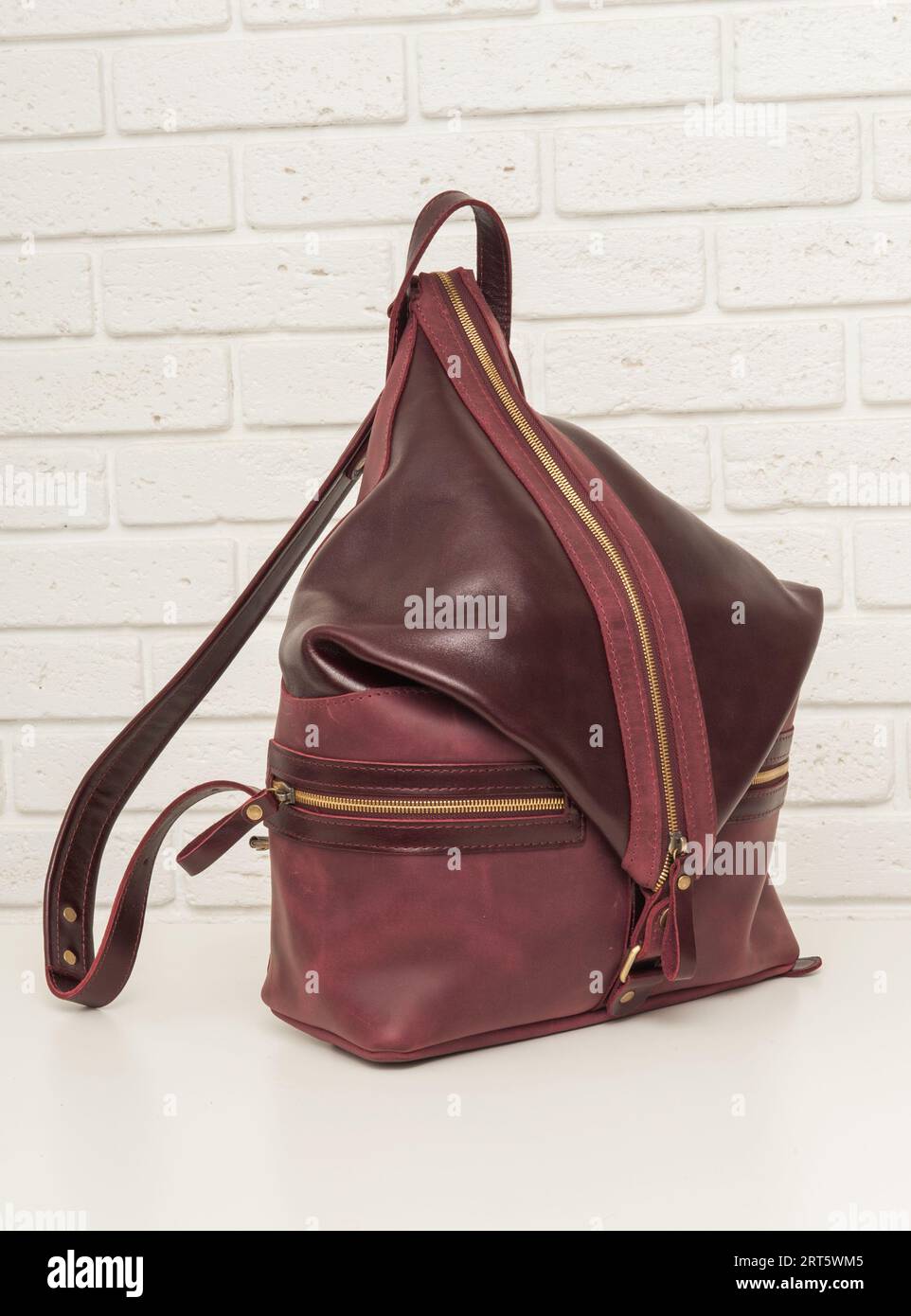 Brown leather backpack bag on white brick background Stock Photo