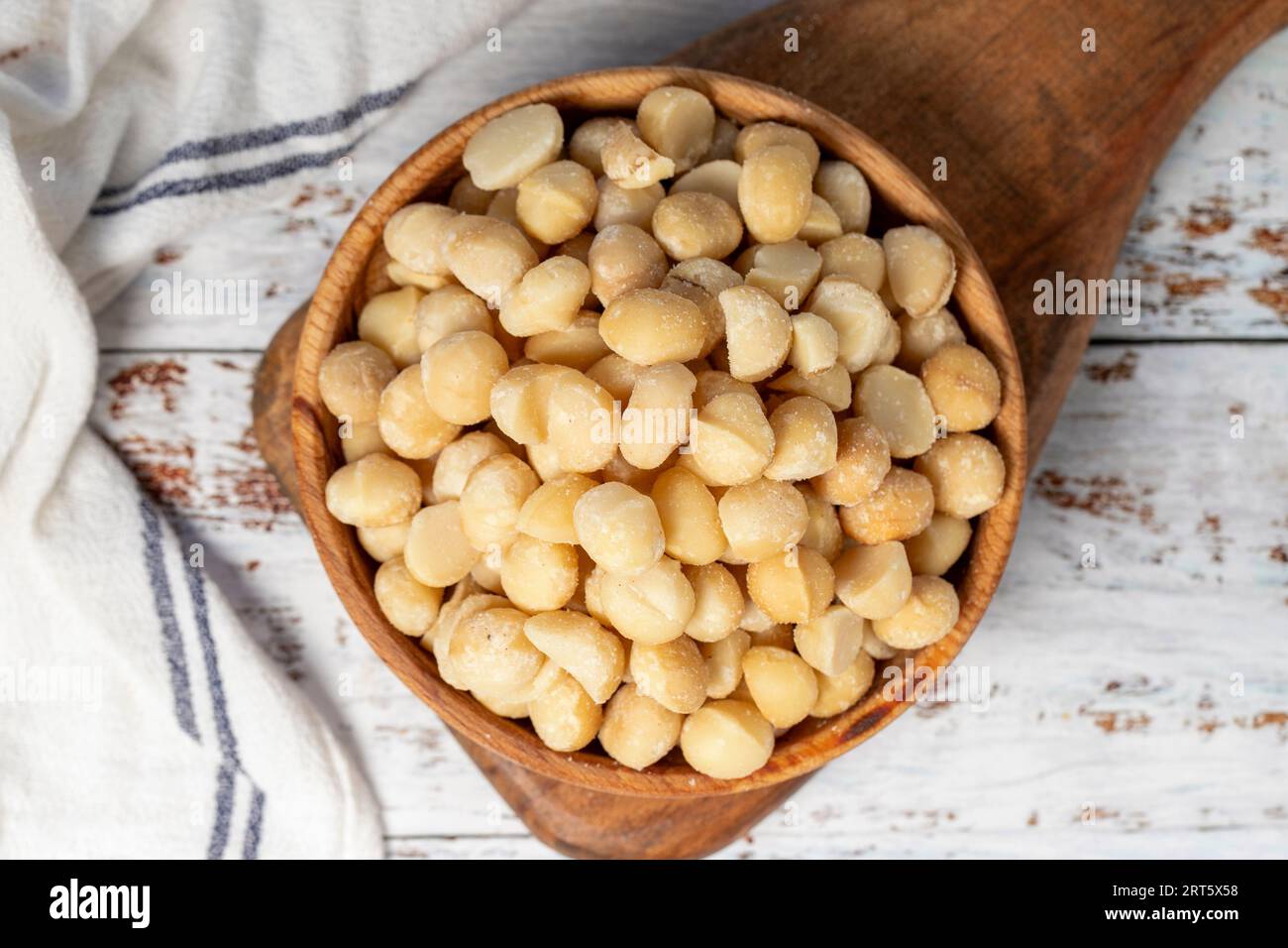 Macadamia nut in wood bowl. Macadamia nuts peeled on white wood background. Top view Stock Photo