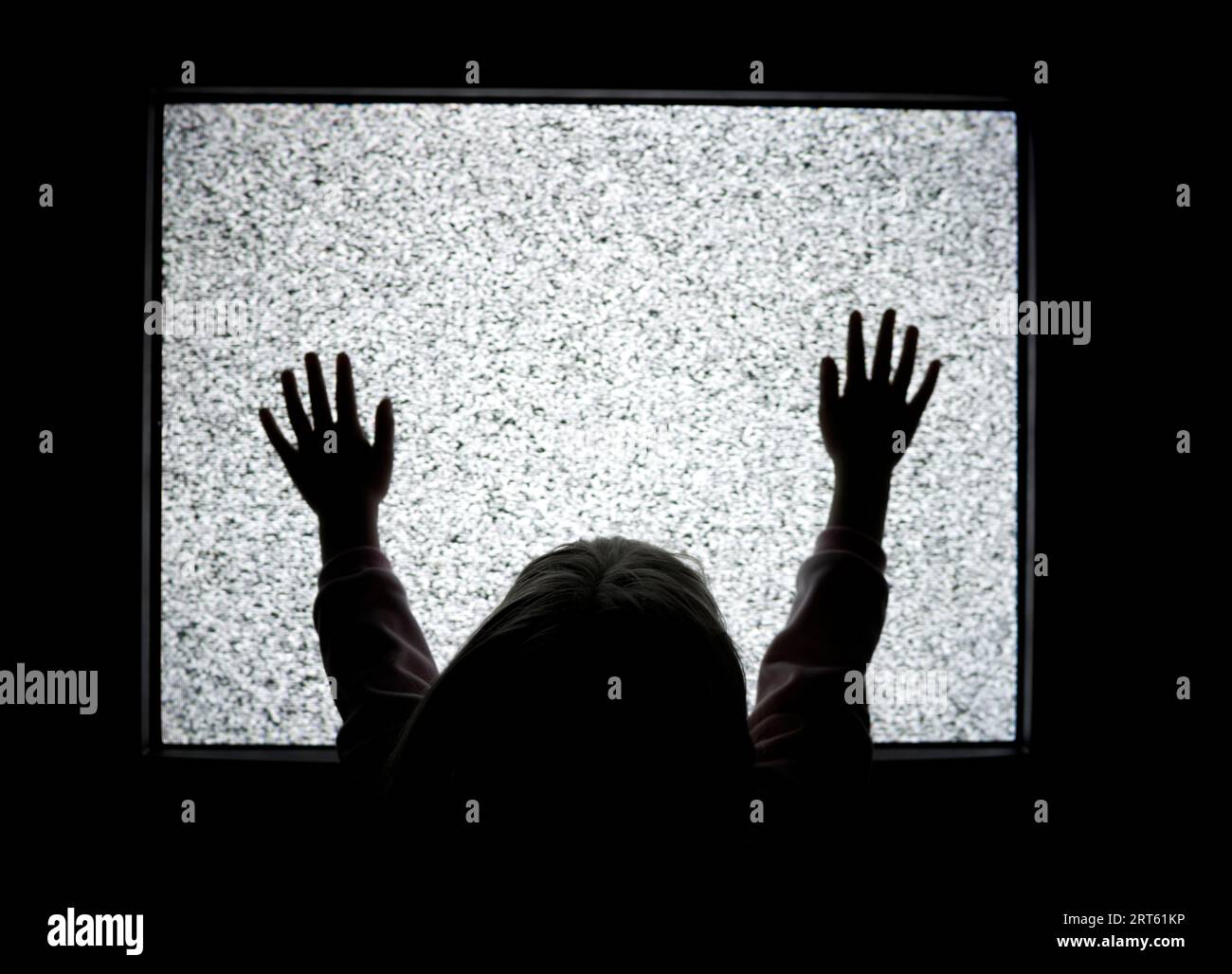 Girl holds hands up to static TV. Stock Photo