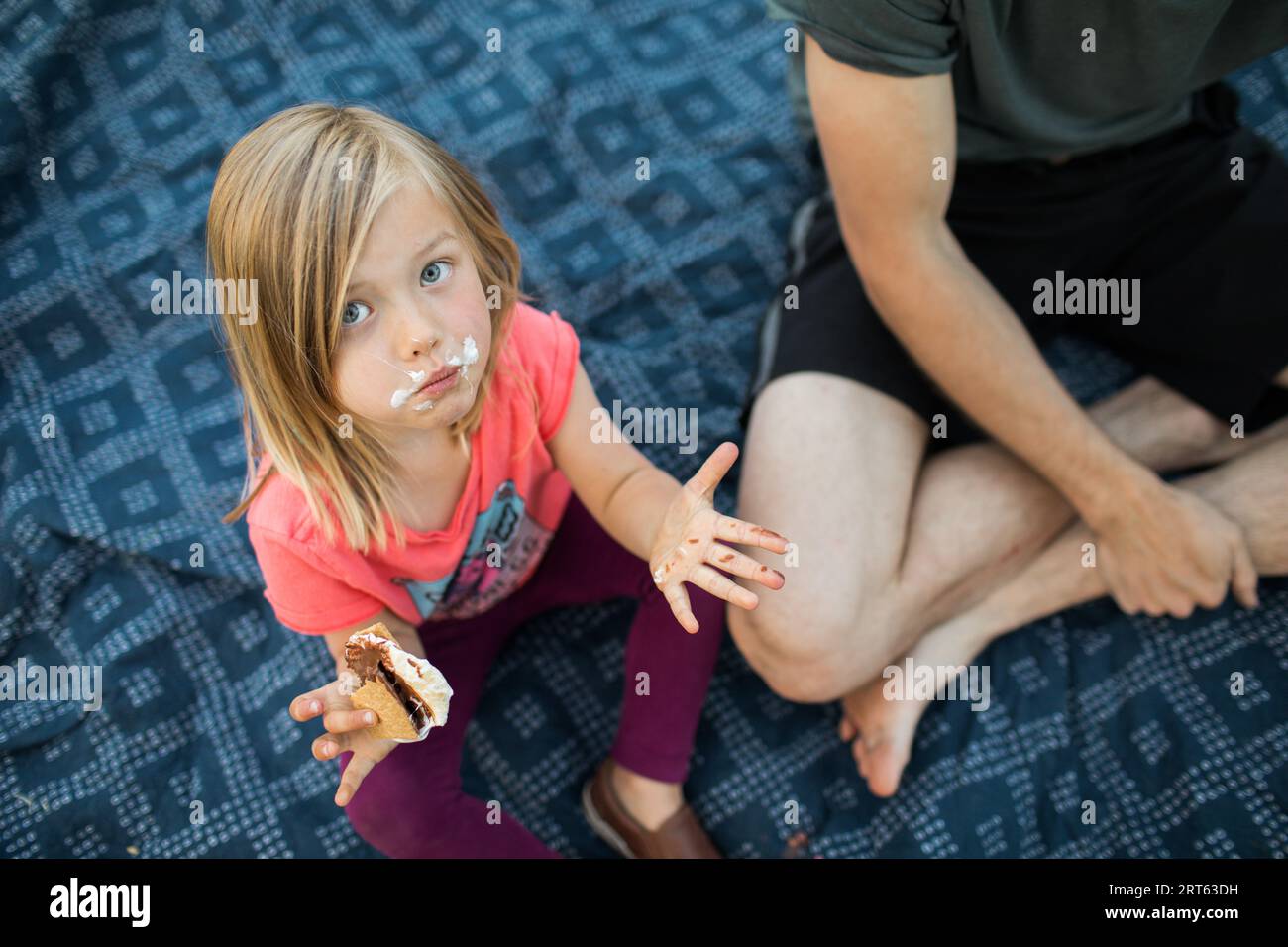 Toddler with face in s’mores on a blanket during their campfire. Stock Photo