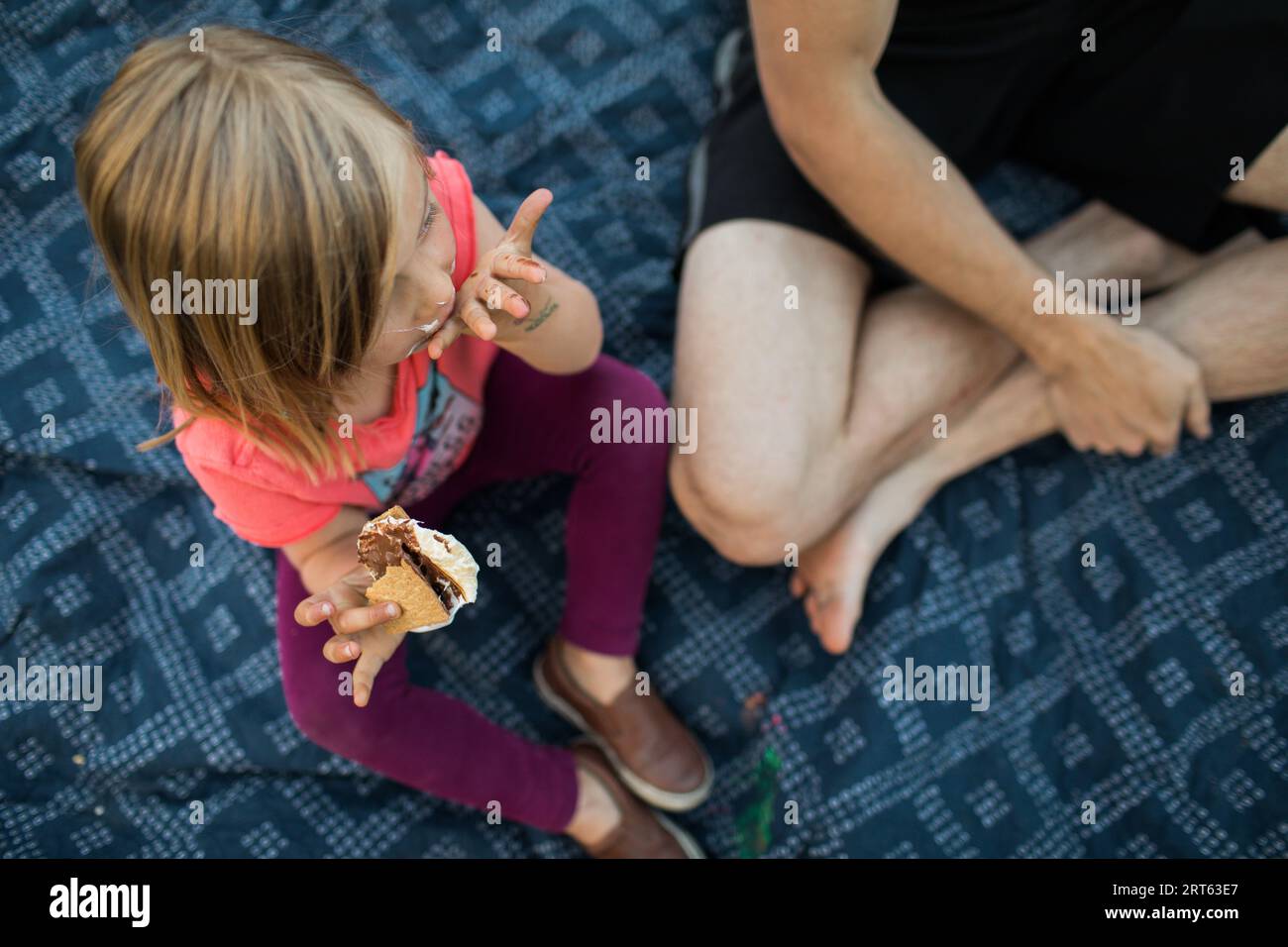 Father and toddler enjoy a s’more by campfire Stock Photo