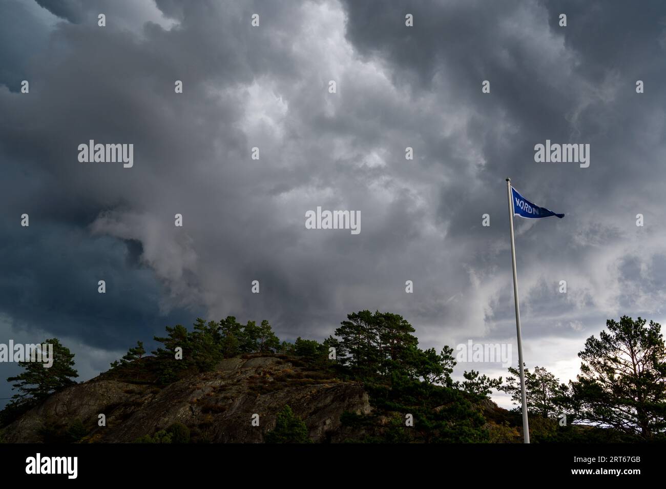 A pennant is flapping in the wind with dramatic storm clouds in the Kragero archipelago a summer day in August. Telemark, Norway. Stock Photo