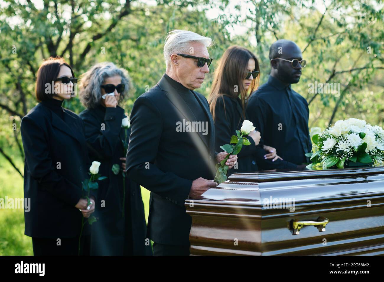 Grieving friends and relatives of passed away person with white roses