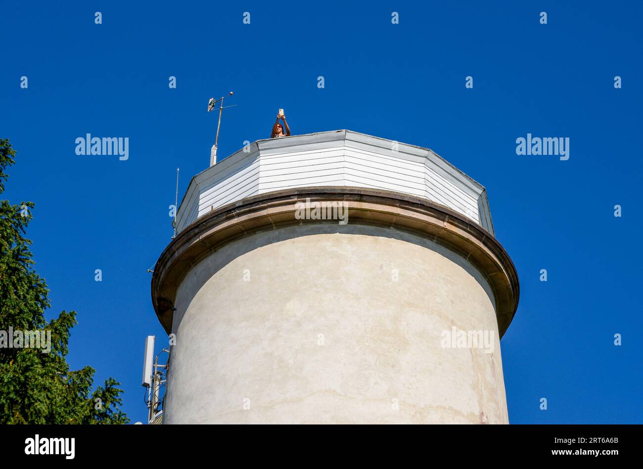 A girl takes photos from the top of the old, decommissioned lighthouse which sits in a forest glade on the narrow Jomfruland island, Telemark, Norway. Stock Photo