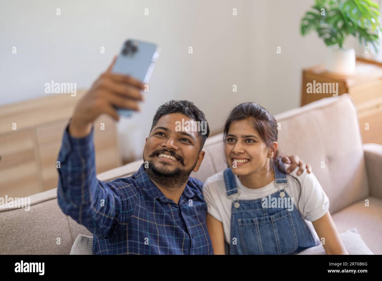 Happy cute young indian couple taking selfie at home sitting on the ...