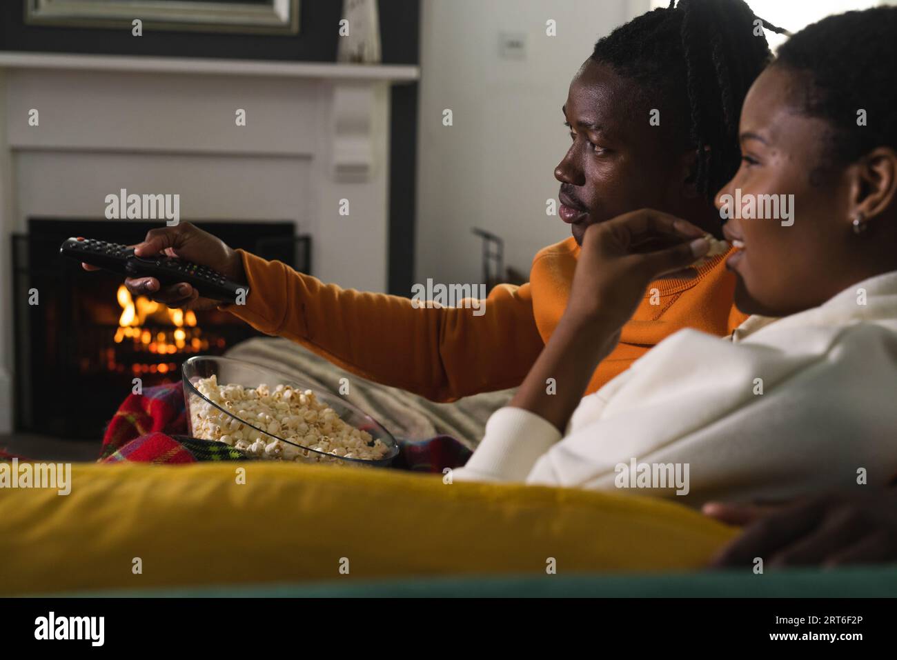 African american couple relaxing at home watching tv and eating popcorn ...