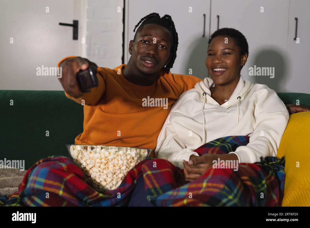 Smiling african american couple relaxing at home watching tv with ...