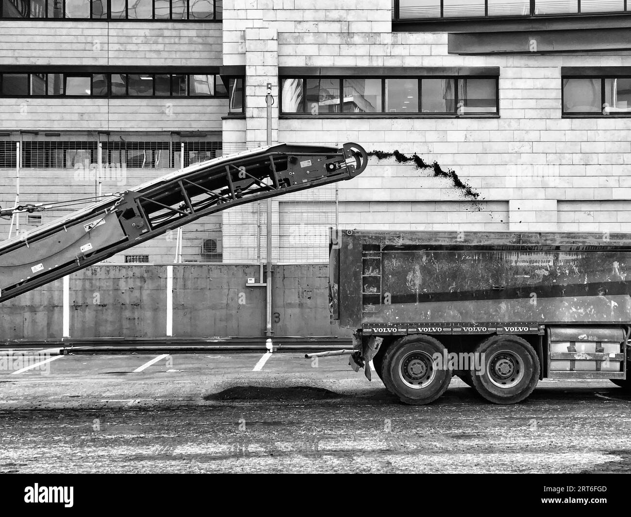 A closeup of a metal truck being filled with asphalt on new road Work day Stock Photo