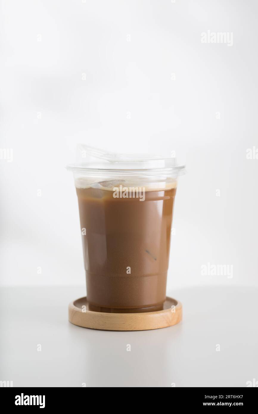 Iced cappuccino in a plastic glass on a white wooden table, minimalist ...