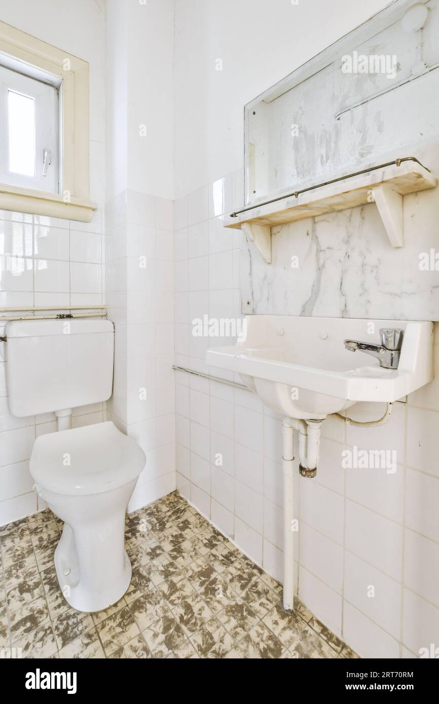 Wall hung toilet and small sink in corner in lavatory room with beige